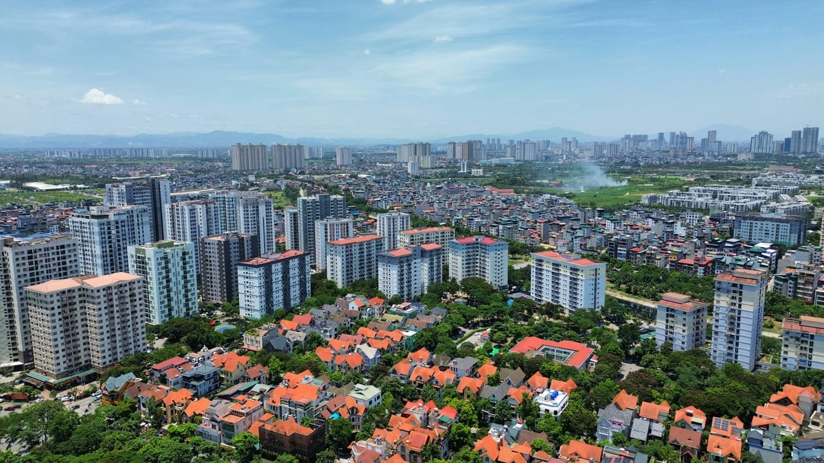 Aerial view of Hanoi with orange-roofed villas in the foreground, apartment blocks in the middle, and the downtown skyline in the distance