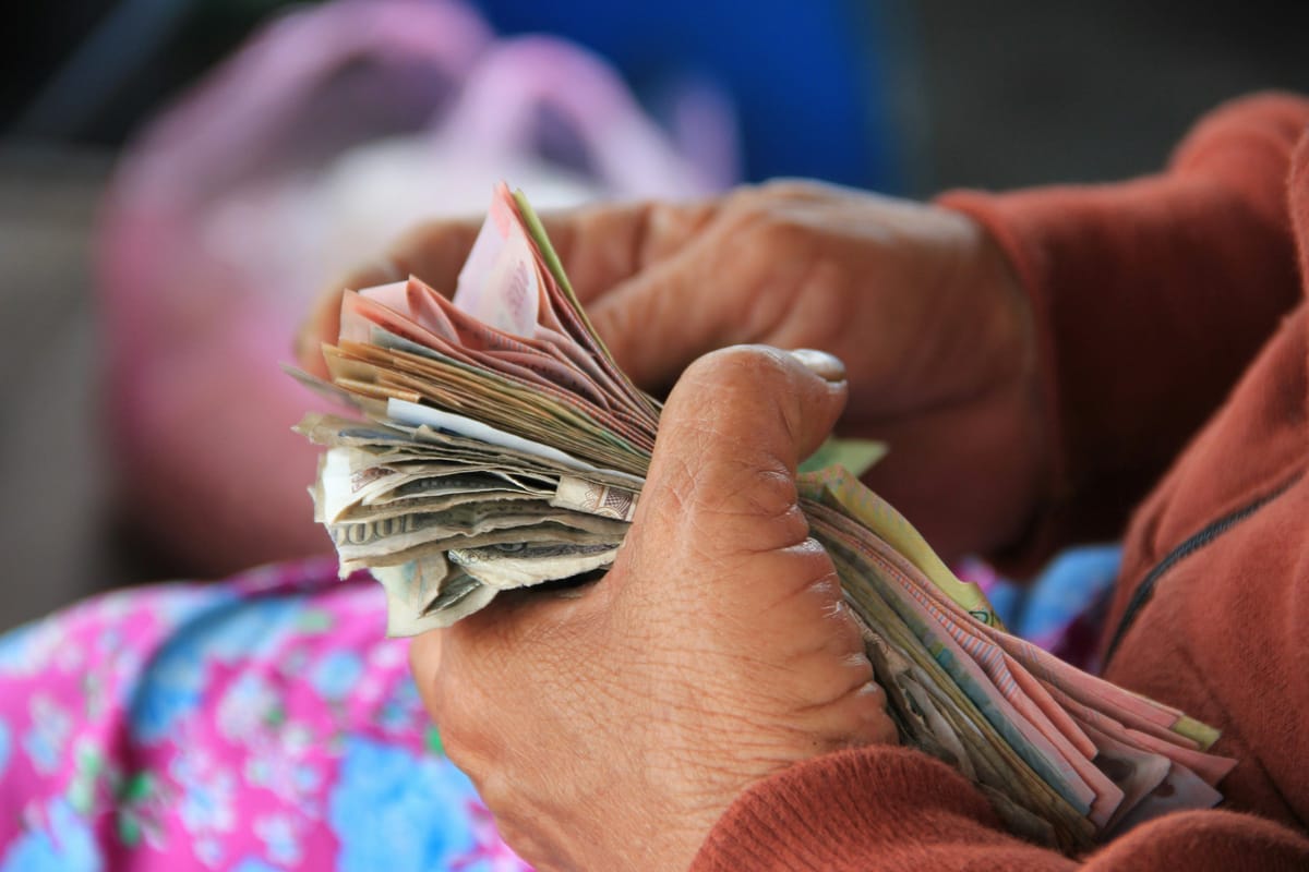 A market vendor's hand holding a stack of Vietnamese dong banknotes