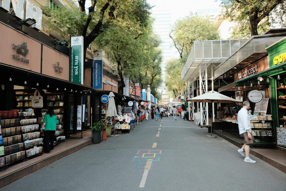 The tree-shaded walkway of Nguyen Van Binh Book Street in Ho Chi Minh City, lined with book stalls and readers