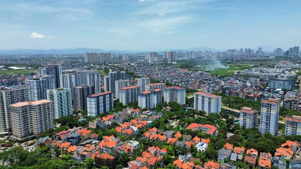 Aerial view of Hanoi with orange-roofed villas in the foreground, apartment blocks in the middle, and the downtown skyline in the distance