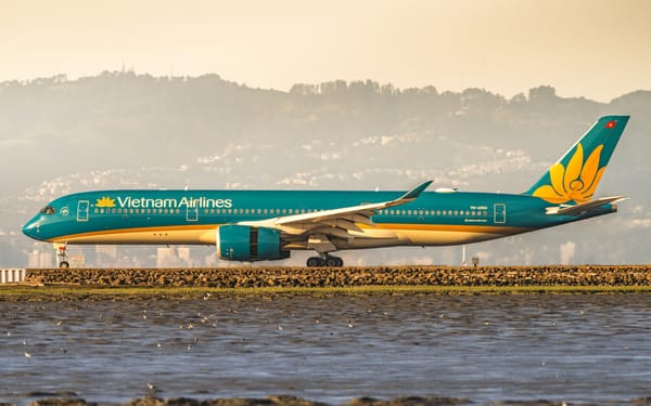 A Vietnam Airlines A350 taxiing along the waterfront in golden morning light